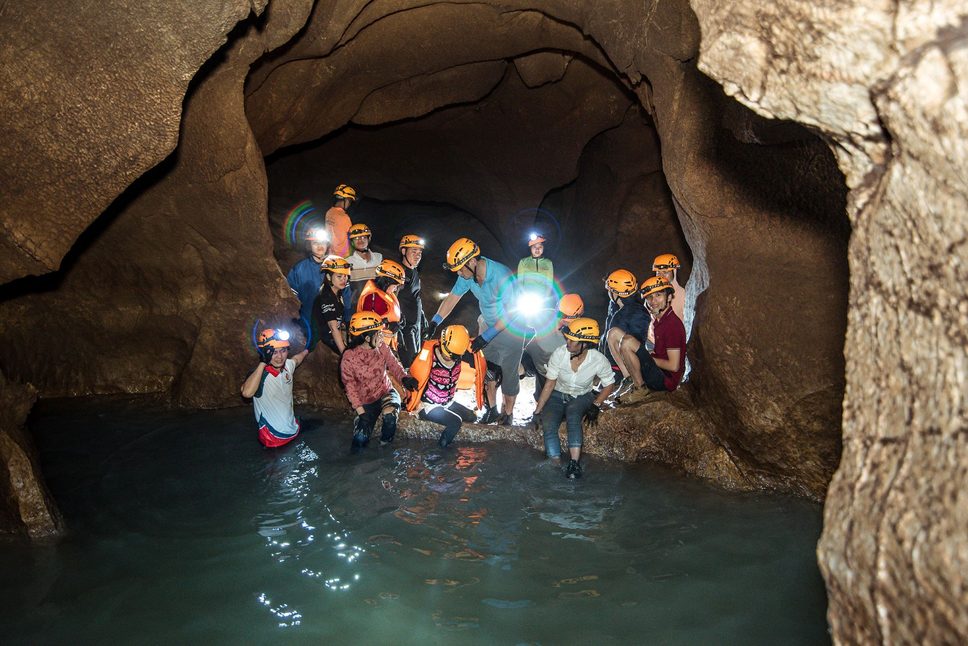 Exploring the cave safely while wearing life jackets to cross underground streams.